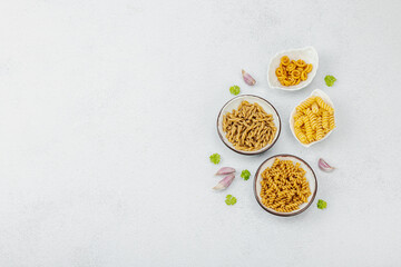 Pasta. Various kinds of uncooked pasta and noodles over light stone background. Traditional Italian