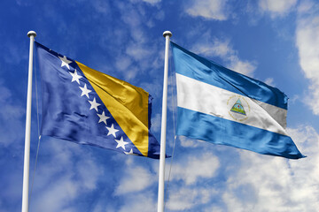 3D illustration. Bosnia and Herzegovina and Nicaragua flags waving in the sky. High detailed waving flag. 3D render. Flags fluttered in the cloudy sky, symbolizing diplomatic relations.