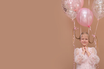 Banner blonde girl with pigtails in a pink dress with balloons on a brown background. Copy space.