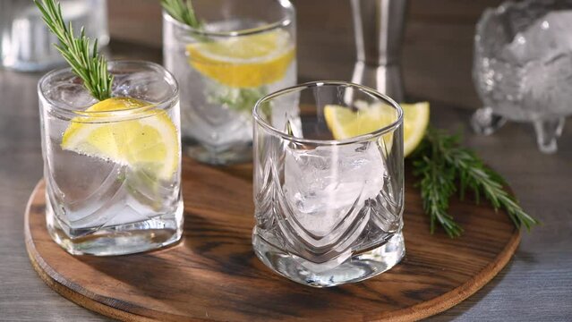 Preparing a cool cocktail Gin with tonic, lemon and rosemary. Real time.