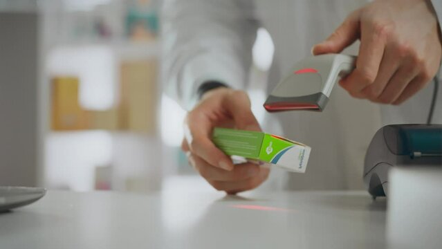 In a pharmaceutical center, a medical worker holds an electronic scanner in his hands. European employee in slow motion dispensing medicines at the checkout counter, adhering to pharmacy standards