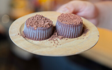 Close-up hands of woman holding a homemade chocolate cupcakes on wooden plate.