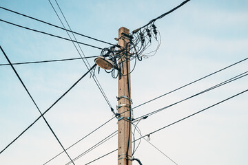Street light with electricity utility pole and messy electrical wires, low angle view