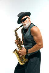 Artistic mature man with beard dressed vintage fashion outfit plays golden saxophone against white studio background. Concept of music, festivals, contemporary art, hobby, creativity. Ad