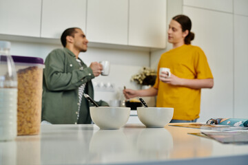 Two young men are enjoying coffee together in a modern apartment.