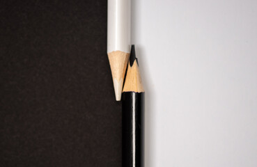Fototapeta premium Black and white pencils isolated on white and black background, concept with black and white, Black And White Pencils Against Contrasting Background To Illustrate Racial Diversity Concept 