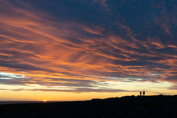 A couple enjoying amazing sunset by the Barents Sea, Norway