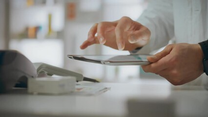 A pharmacy worker holds a touchscreen tablet in his hands and concentrates on working at an electronic tablet at a point of sale of medicines. Pharmaceuticals, cinematic frame, medicine.