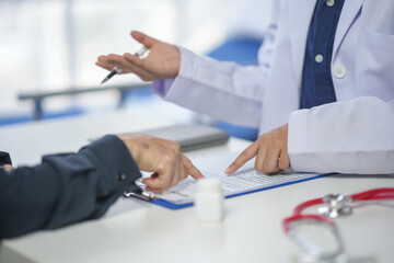Doctor and patient discussing medical records during a consultation, focusing on diagnosis and...