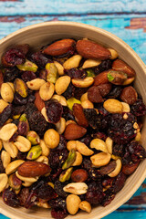 Mix of nuts and dried fruits in a wooden bowl on a wooden background, student mix of nuts and dried fruits, healthy snack, nuts and dried fruits