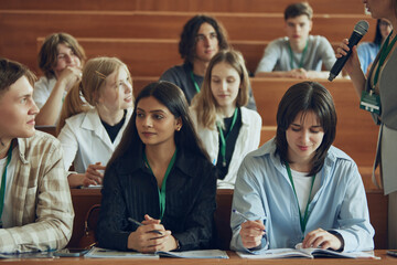 Group of multiethnic people, students sitting in well-lit university auditorium, listening to lecturer, attending workshop. Concept of education, youth, workshop, knowledge