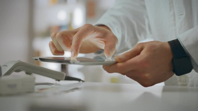 Retail. A pharmacist assistant works on an electronic tablet in a pharmaceutical center. A young Caucasian man holds a touch tablet in his hands does not violate the rules of service, shelf