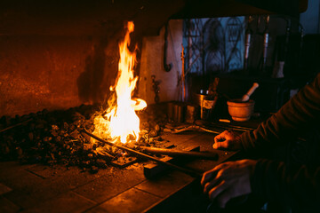 Artisan blacksmith working metal at fiery forge