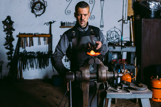 Skilled blacksmith forging hot metal in workshop