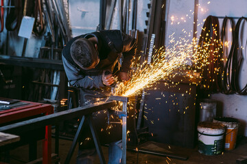 Blacksmith working with angle grinder in workshop