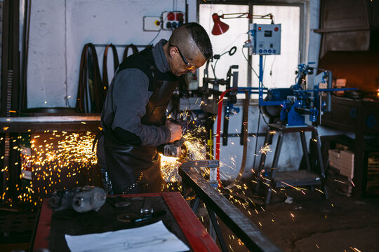 Blacksmith Crafting Metal with Angle Grinder in Workshop