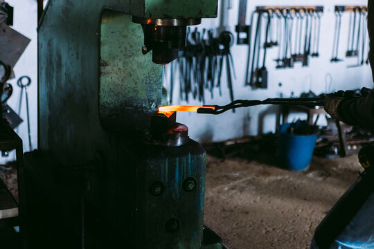 Traditional blacksmith working metal with hammer and forge