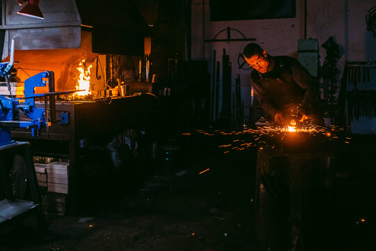Blacksmith shaping metal on anvil in workshop