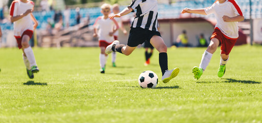 Kids as Football Soccer Players Running with Ball. Footballers Kicking Play League Match During Sunny Day. Two Teams in Sport Competition. Teenage Soccer Players Running in a Duel and Kicking Ball