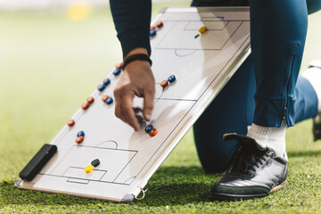 Football Coach Using Soccer Tactics Strategy Board. Coach explaining the game plan to school soccer...