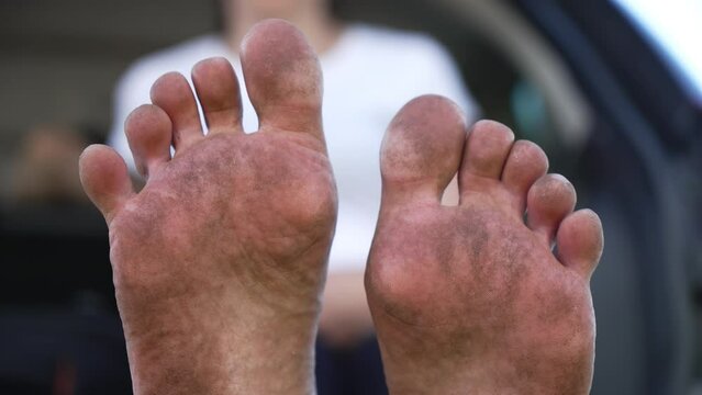 Close Up Of Dirty Bare Feet In Car. Dirty female foots after walking barefoot at hiking. Unrecognizable girl resting barefoot sitting in car trunk