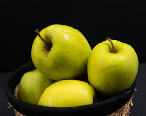 Green juicy apples in a jute basket on a black background, juicy fruit, healthy apples, juicy green apples in basket ,apples close up