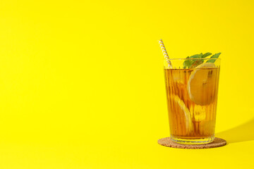 Cold tea with orange slices and mint leaves on a yellow background