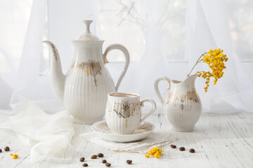 Modern still life with a coffee set and a spring mimosa branch on a light windowsill