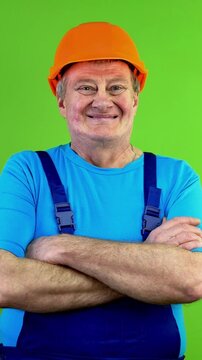 Worker in overalls smiling and crossing his arms.