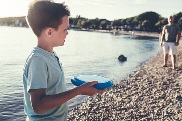 Father and son playing frisbee at beach. Playing frisbee with my dad at sea during sunset.