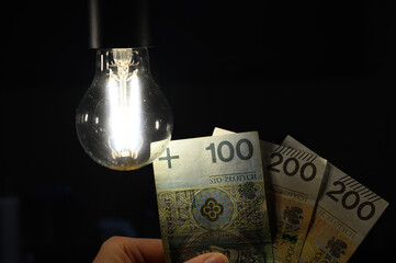 Świecąca żarówka na banknoty trzymane w ręce 