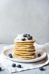 A stack of pancakes with fresh blueberries, cheese cream and glass of milk. Delicious homemade breakfast.