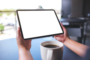 Mockup image of a woman holding digital tablet with blank white desktop screen in cafe