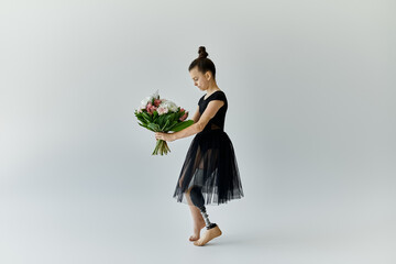 A young girl with a prosthetic leg holds a bouquet of flowers while wearing a black gymnastics...