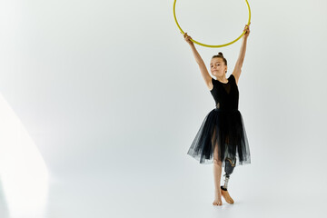 A young girl with a prosthetic leg performs a graceful gymnastic pose with a hula hoop.
