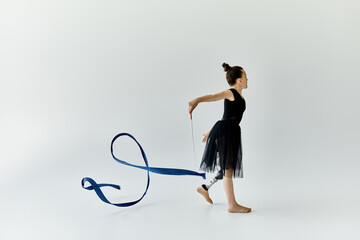 A young girl with a prosthetic leg performs a graceful gymnastics routine with a ribbon.