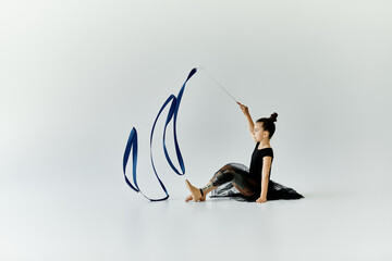A young girl with a prosthetic leg performs a graceful ribbon dance in a studio.