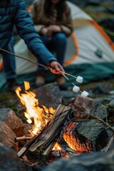 Fototapeta premium A person roasting marshmallows over an open flame at night, surrounded by nature