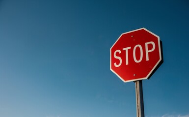 Low angle shot of stop traffic sign against a clear blue sky background.