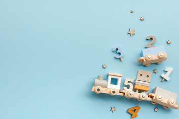 Wooden toy train with numbers on pastel blue background. Early learning for babies and toddlers,...