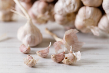 Ripe organic garlic clove and bulb on white wooden background.  Close-up. Selective focus.