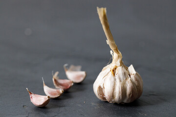 Ripe organic garlic clove and bulb on black stone background.  Close-up. Selective focus.