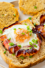 Baked Bacon and Eggs in Bread on White Plate with Fresh Green Onion Close-Up
