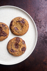Homemade chocolate chip cookies in ceramic plates on rustic background.