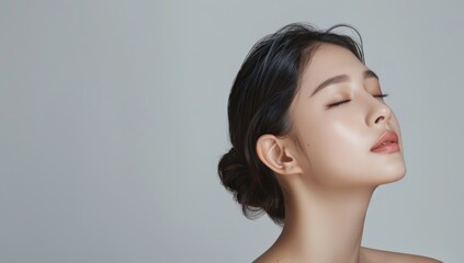 Beautiful woman with perfect skin portrait on gray background, close up of beautiful young asian model in profile looking away from camera