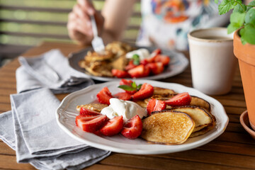 Delicious summer breakfast with pancakes, fresh strawberries and cream