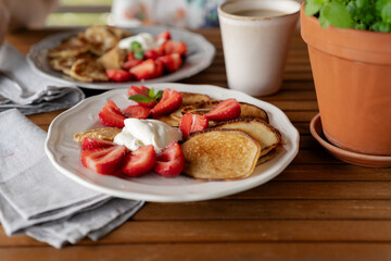Delicious summer breakfast with pancakes, fresh strawberries and cream