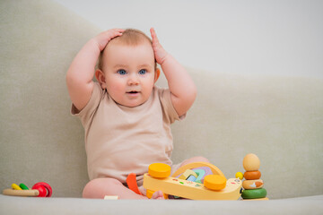 A baby is sitting on a couch with a toy truck in front of him.