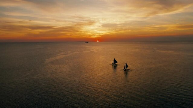 Sunset above the sea surface with sail boats, aerial view Boracay, Philippines. Reflected sun on a water surface. Sunset over ocean. Seascape, Summer and travel vacation concept