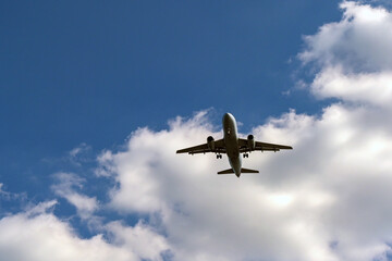 Unmarked holiday jet flying overhead to land at an airport. No people. Copy space.